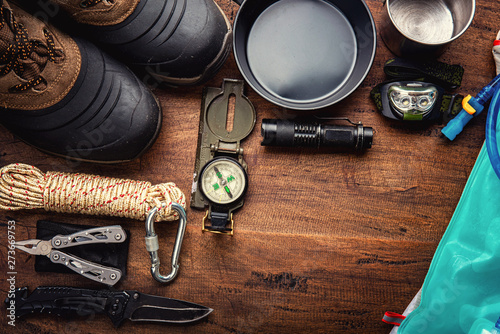 Outdoor travel equipment planning for a mountain trekking camping trip on wooden background. Top view - vintage film grain filter effect styles photo