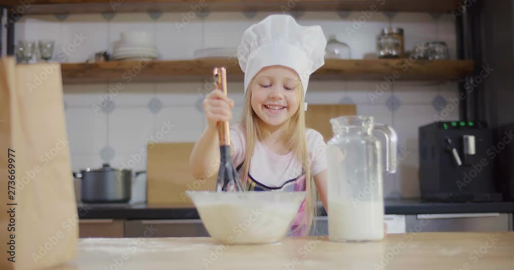 Little girl mixes dough in the bowl and smiles Little girl mixes dough in the bowl and smiles