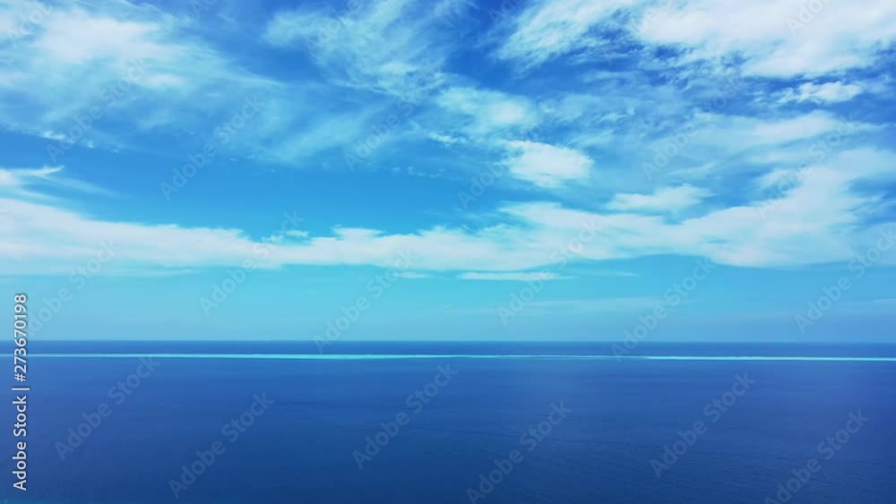 horizon shot of open blue turquoise tropical ocean under a bright blue sky with white clouds, Aerial drone left panning horizon shot of open blue turquoise tropical ocean under a bright blue sky with white clouds, Aerial drone left panning