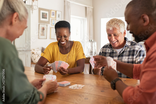 Mature friends playing cards at home