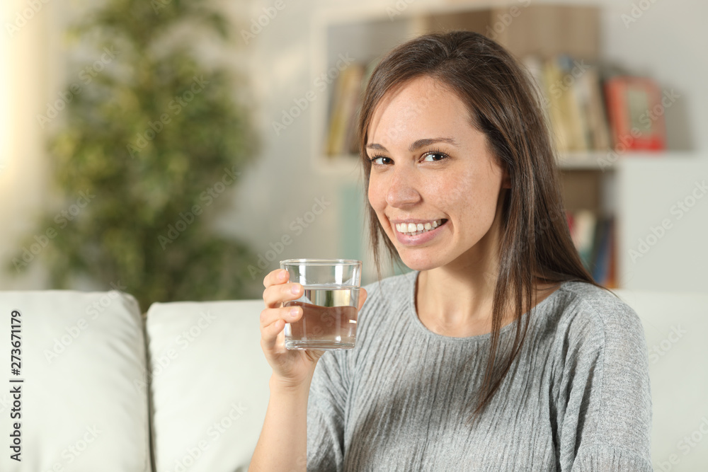 Woman holding a glass of water looks at you Woman holding a glass of water looks at you