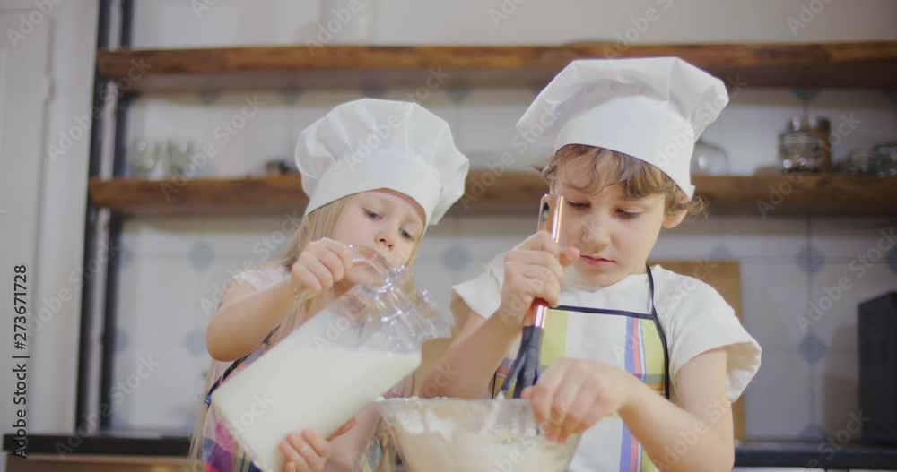 Children prepare dough for cooking. Girl adds milk, boy mixes ingredients