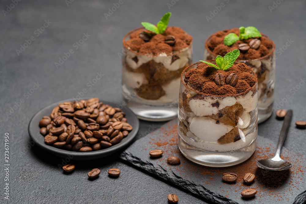 Classic tiramisu dessert in a glass on stone serving board on dark concrete background Classic tiramisu dessert in a glass on stone serving board on dark concrete background
