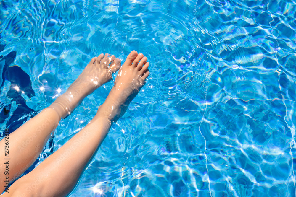 Relaxing in a pool Top view Girl with clean smooth skin is wetting feet in a pool with blue water Photo with copy space