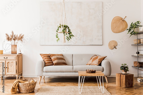 The stylish boho compostion at living room interior with design gray sofa, wooden coffee table, commode and elegant personal accessories Fototapet