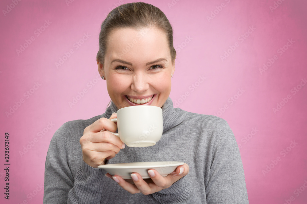 young woman enjoys a cup off coffee or tea in front of a pink background young woman enjoys a cup off coffee or tea in front of a pink background