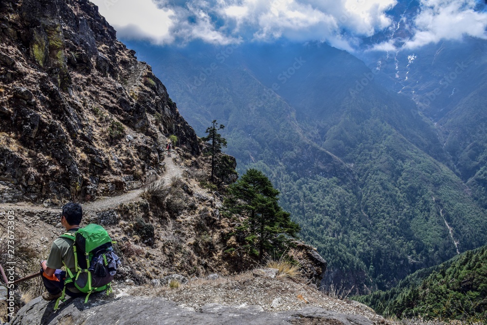 Hiker in the mountains of Nepal with forest and clouds on background 