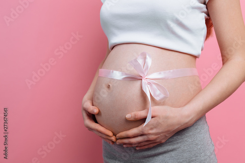An image of a pregnant woman with a pink ribbon on her belly