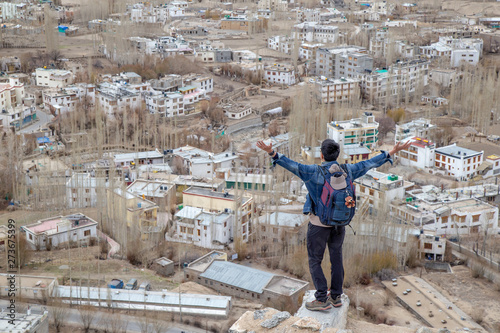 Traveler man standing on Leh Ladakh city view from Shanti Stupa. Beautiful amazing village in the valley with snow mountain at background. Ladakh, India. © chayakorn