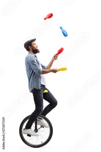 Male juggler on a unicycle juggling with clubs photo