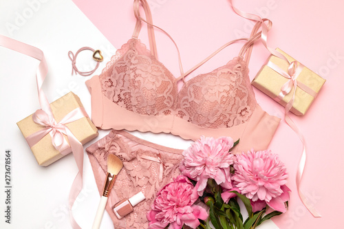 Set of female necessary accessories, gift wrapping boxes with pink ribbons, a bouquet of peonies and underwear on a flat lay. fashion. Copy space