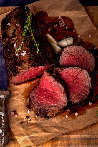 Roast beef from tenderloin A large piece is cut into pieces. A large portion of meat served on a wooden board. Close up and vertical orientation.