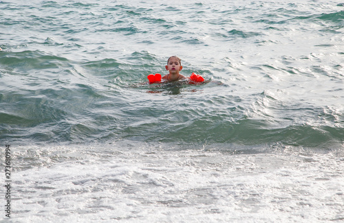 The boy in red inflatable sleeves bathes on the sea © vitec40