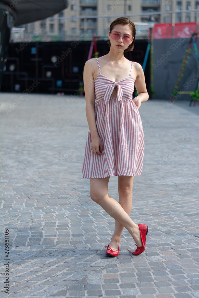 Asian Chinese model girl influencer street shot. Wearing pink dress and red shoes. Street Graffiti background. Asian Chinese model girl influencer street shot. Wearing pink dress and red shoes. Street Graffiti background.