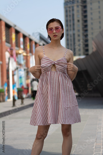 Asian Chinese model girl influencer street shot. Wearing pink dress and red shoes. Street Graffiti background.