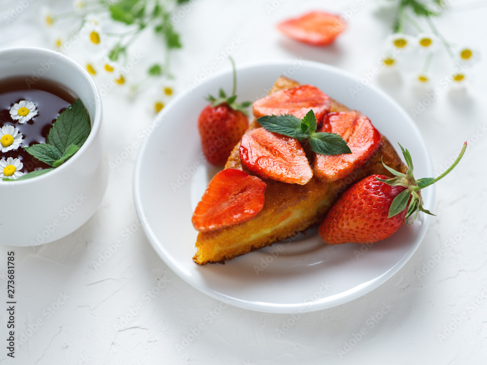 very tasty carrot cake decorated with strawberries on a white table and a Cup of fragrant flower tea very tasty carrot cake decorated with strawberries on a white table and a Cup of fragrant flower tea