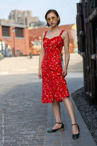 Asian Chinese model girl influencer street shot. Wearing red floral printed dress. Street view background.