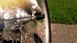 Focus on the tire of the electric bicycle with wheel motor at sunny summer day and light leaks  with green grass and asphalt on the background. E bike motor with sun reflections. Close up.