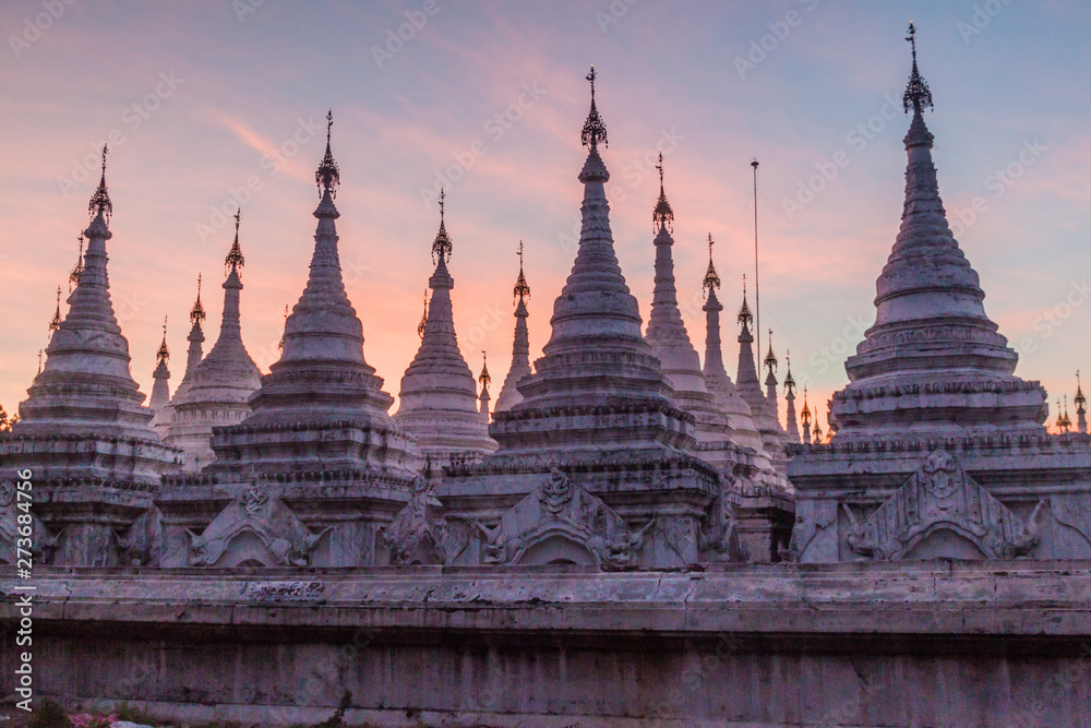 Fototapeta premium White stupas around Sandamuni (Sandamani or Sandar Mu Ni) pagoda during dusk in Mandalay, Myanmar