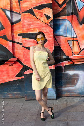 Asian Chinese model girl influencer street shot. Wearing yellow patterned sundress.  Street view background.