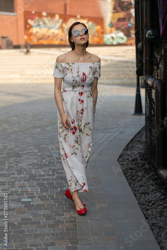 Asian Chinese model girl influencer street shot. Wearing white printed floral patterned jumpsuit.  Street view background. © fan