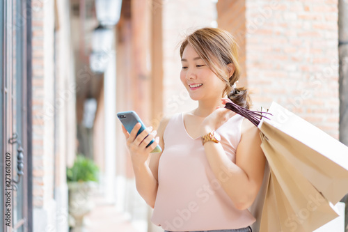 Photography Smiling Asian Thai girl holding gift in shopping bags She Compares prices on mob