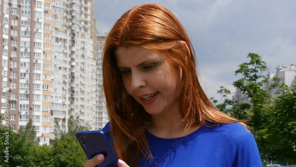 Young beautiful girl with red hair, in the city, can not find information in a mobile phone. Young beautiful girl with red hair, in the city, can not find information in a mobile phone.