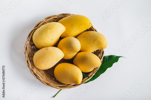 Yellow mango in a basket on a white background