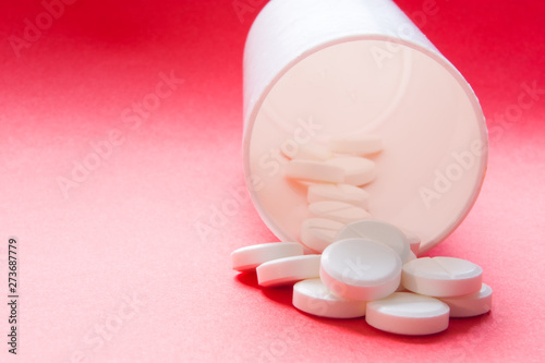 White round capsules spilled from white container for drugs of white blue gradient background with clean area for inscriptions close up. Photos for use in pharmaceutical industry, medicine, treatment