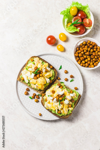 Breakfast toasts, soft scrambled eggs avocado goat cheese spicy chickpeas. Top view, space for text.