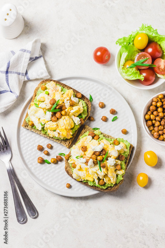 Breakfast toasts, soft scrambled eggs avocado goat cheese spicy chickpeas. Top view, space for text.