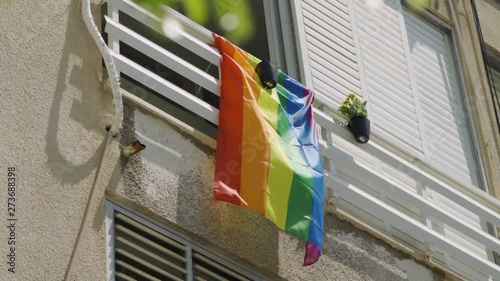 LGBTQ flag blows in the wind - hanging from a balcony