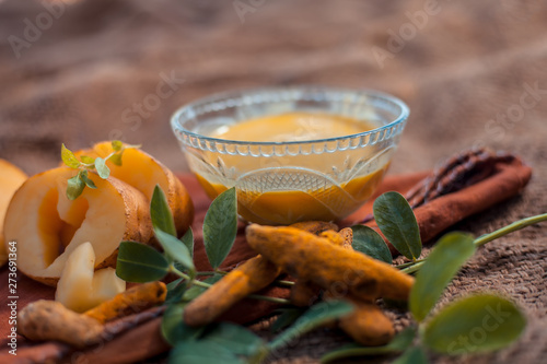 Potato face mask consisting of grated potato and some turmeric powder or haldi in a glass bowl on jute bags surface to brighten the skin, kills bacteria and germs.