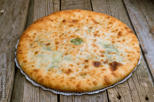 Ossetian pie with spinach on wooden background