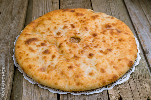 Ossetian pie with meat on wooden background