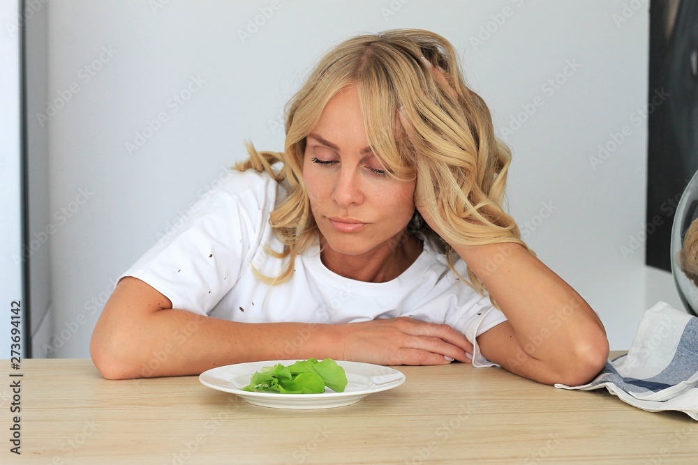 I'm fed up with untasty disgusting salad. Close up unhappy grimacing sad upset lady looking down at plate of lettuce on table. I'm fed up with untasty disgusting salad. Close up unhappy grimacing sad upset lady looking down at plate of lettuce on table.