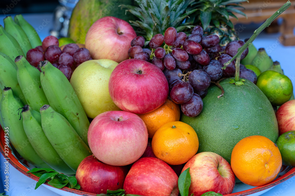 Assortment of fresh fruit banana, grapes, orange, apple, pineapple, tangerine and grapefruit on a tray. Closeup Assortment of fresh fruit banana, grapes, orange, apple, pineapple, tangerine and grapefruit on a tray. Closeup