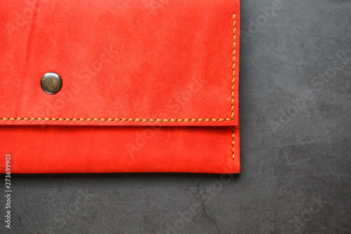 Red leather wallet on a dark background top view. Close-up, purse details, rivet and firmware