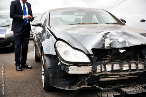 Male Insurance Loss Adjuster With Digital Tablet Inspecting Damage To Car From Motor Accident © Monkey Business