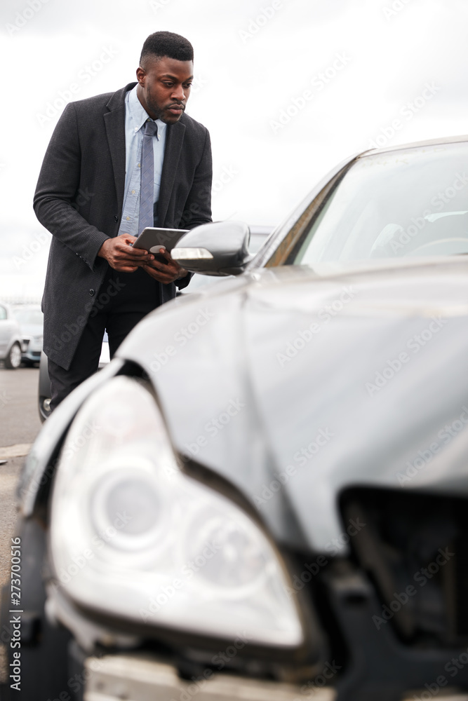 Male Insurance Loss Adjuster With Digital Tablet Inspecting Damage To Car From Motor Accident Male Insurance Loss Adjuster With Digital Tablet Inspecting Damage To Car From Motor Accident