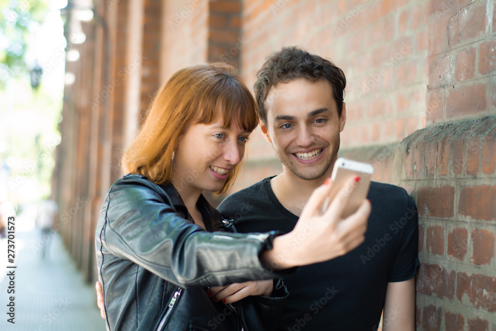 Young couple taking selfie with mobile phone outdoors.