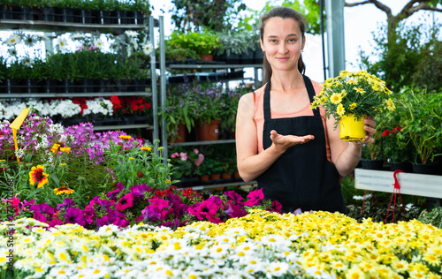 Female gardener demonstrating garden flowers in flowerpots