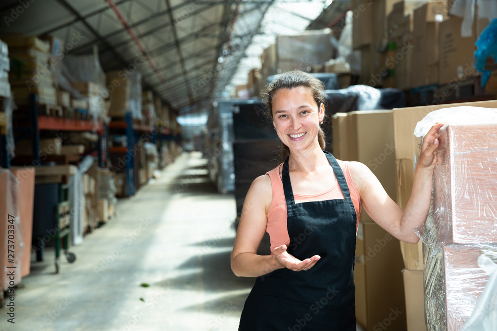 Fototapeta premium Happy female seller holding box in warehouse