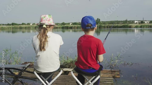 Brother and sister are fishing on the beautiful pond photo