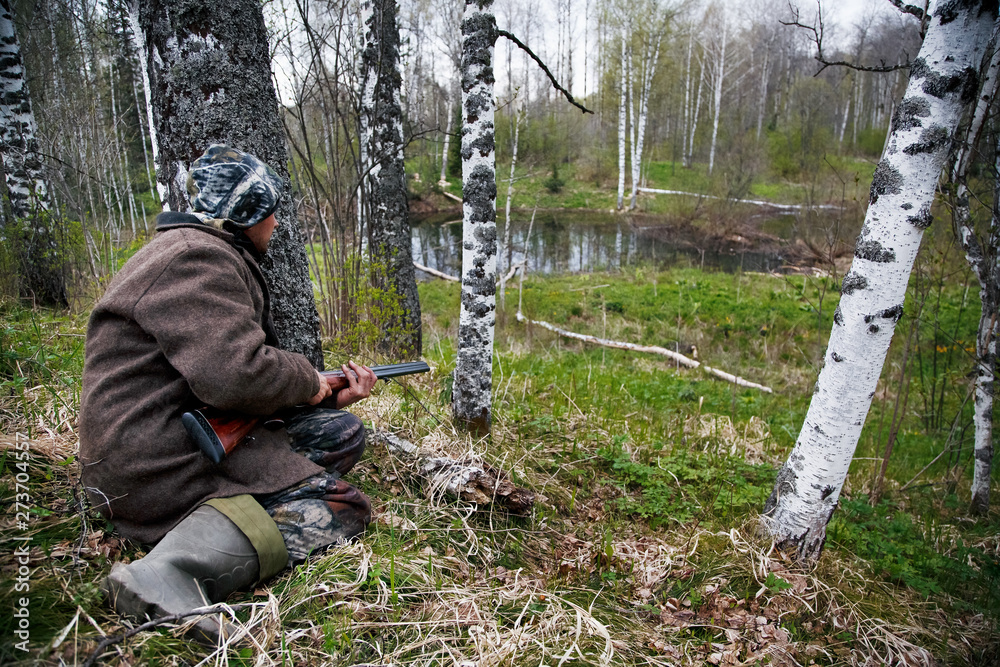 Hunter with a gun sitting in ambush in the woods. Waiting for game. Siberia Hunter with a gun sitting in ambush in the woods. Waiting for game. Siberia