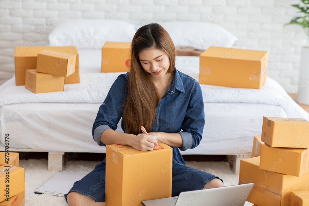 SME entrepreneur of Young women working with laptop and writing customer address for send order Online shopping at home,Cheerful and Happy with box for packaging in home,Startup and Freelance Concept