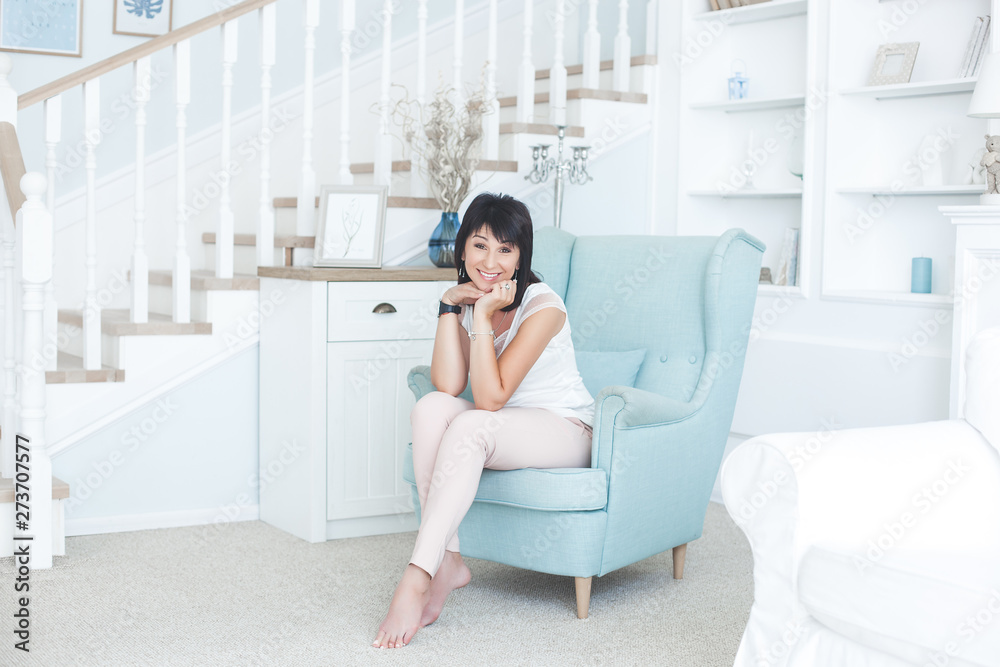 Attractive adult woman sitting on the couch indoors. Beautiful middle-age female at home. Portrait of 35-40 years woman. Attractive adult woman sitting on the couch indoors. Beautiful middle-age female at home. Portrait of 35-40 years woman.