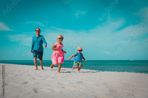 father with little daughters play  run at beach