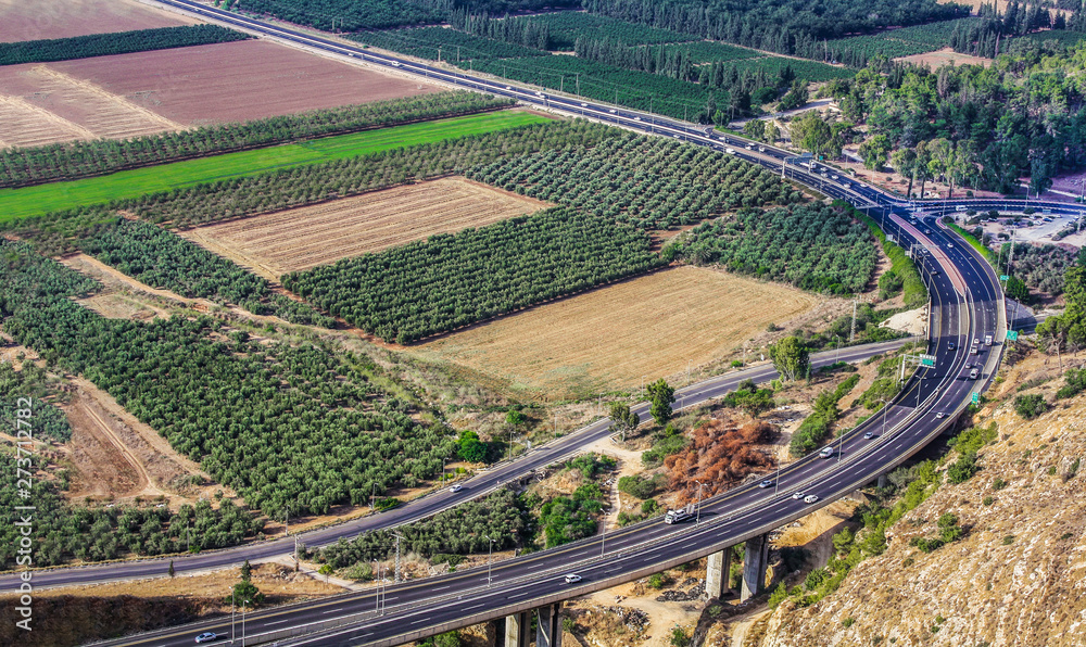 The road to Nazareth. Cars are driving along the highway. View from a height. Fields, forest, pond. Israel. Holy Land.