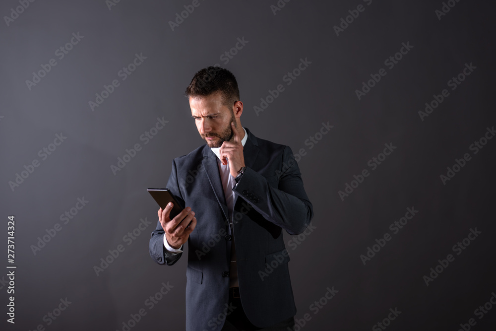 A thinking businessman using his smartphone A thinking businessman using his smartphone